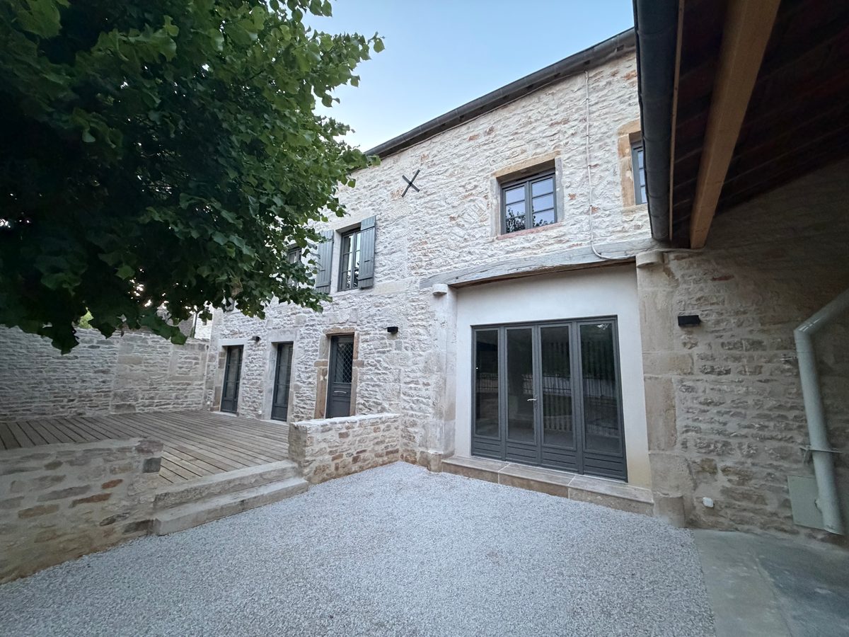 Rénovation d'une façade en pierre avec baies vitrées alu et cour aménagée, chantier Pinto José en Saône-et-Loire